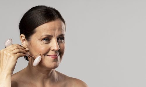 mature-woman-using-rose-quartz-face-roller-with-copy-space